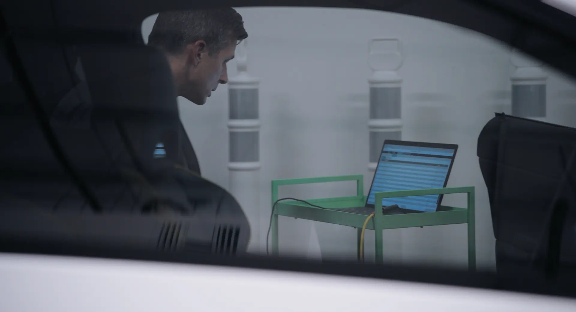 A technician seen through a side window, working on a laptop inside the vehicle.