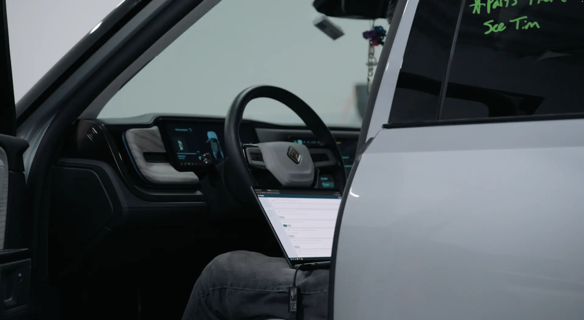 A technician working in the open cabin of an electric SUV.