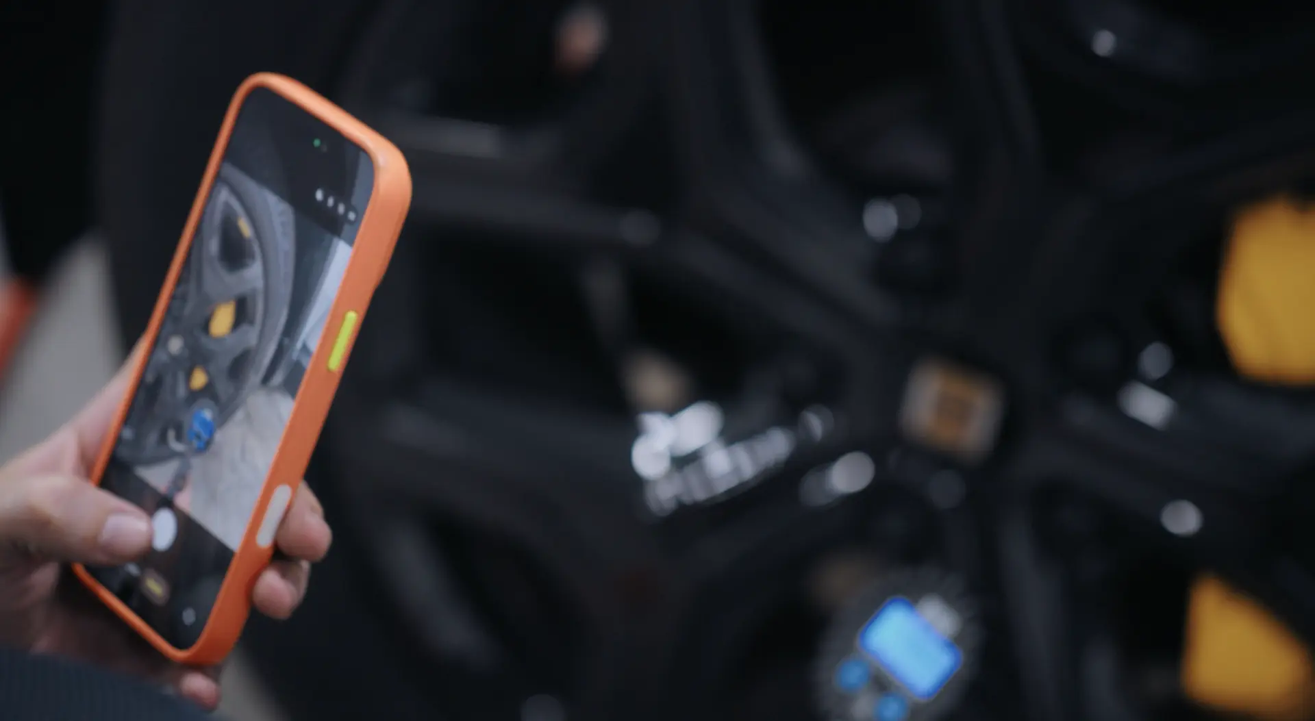 A technician photographing a wheel assembly on a phone to document the work.